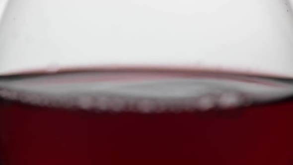 Close Up of a Drop Falling in Glass with Red Wine. Rose Wine on White Background