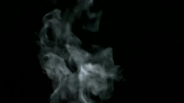 Thick light steam rises smoothly on a black isolated background.