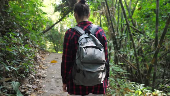 Young Woman with Backpack Walks in Lush Tropical Forest