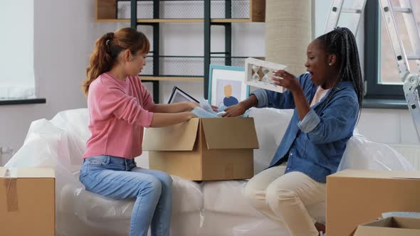 Women Moving to New Home and Unpacking Boxes