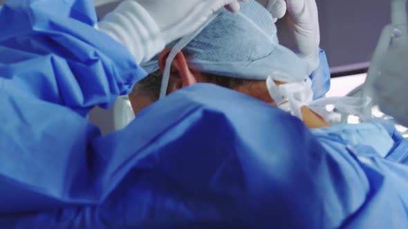 Close-up of female doctor helping male doctor to wear surgical mask in operation theater