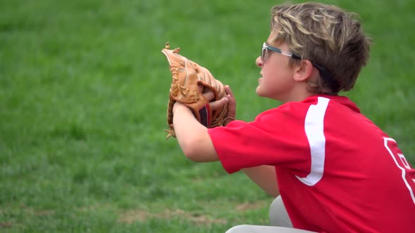 A boy practices playing catch on a little league baseball field.