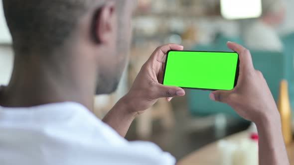 Young African Man Watching Smartphone with Green Chroma Screen 