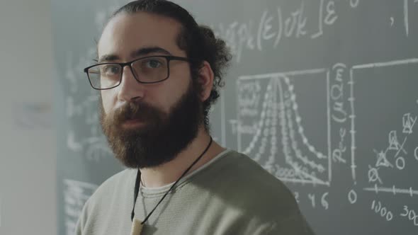 Portrait of Young Bearded Student beside Chalkboard