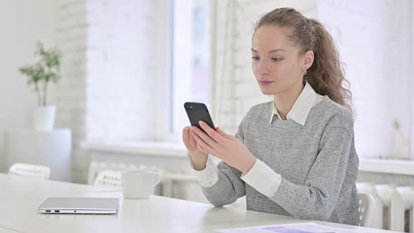 Relaxed Young Latin Woman Using Smartphone in Modern Office 