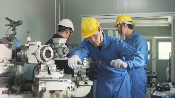 Asian mechanical technicians workers team wear helmet working on milling machine in industry factory