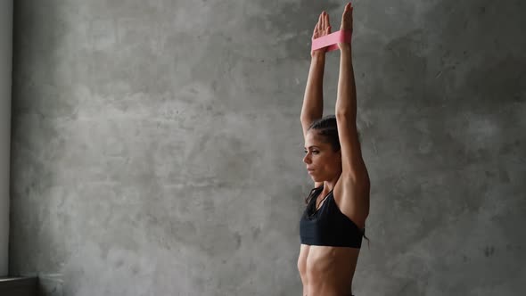 A Sports Girl in Sportswear Shakes Her Muscles with an Elastic Band