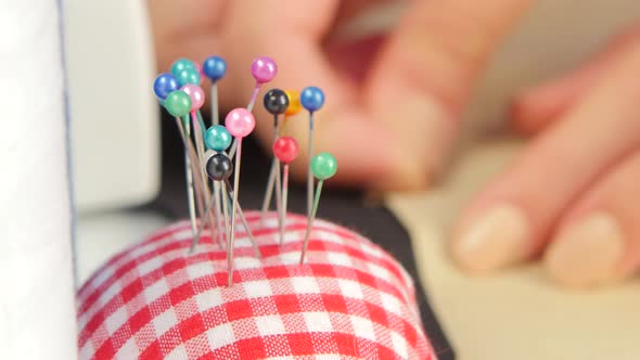 Anonymous Woman Puts Down Her Scissors in Front of a Sewing Machine and Takes a Needle or Pin From