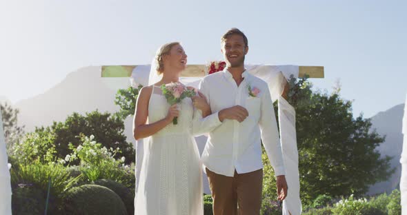 Portrait of happy caucasian newly wed couple, walking down the altar outdoors