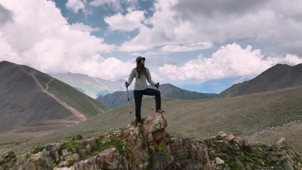 A Young Attractive Caucasian Caucasian Woman in Trekking Clothes with Trekking Sticks Stands on Top