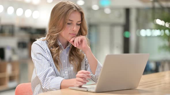 Businesswoman Thinking and Working on Laptop in Office 