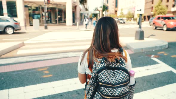 Young Adult Student with a Backpack Walking on City Crosswalk in Slow Motion