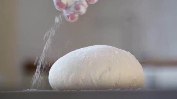 Man Sprinkling Flour Over Fresh Dough on Kitchen Table