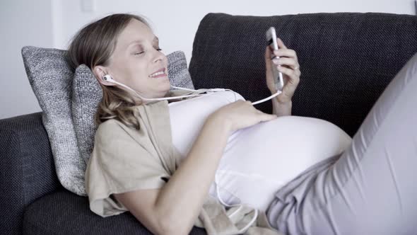 Relaxed Young Pregnant Woman Listening To Music