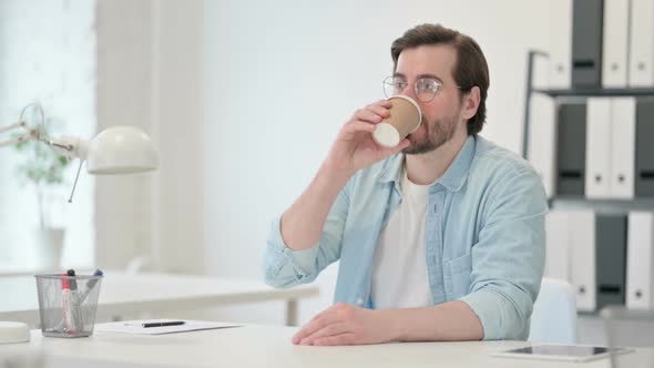 Relaxed Young Man Drinking Coffee at Work