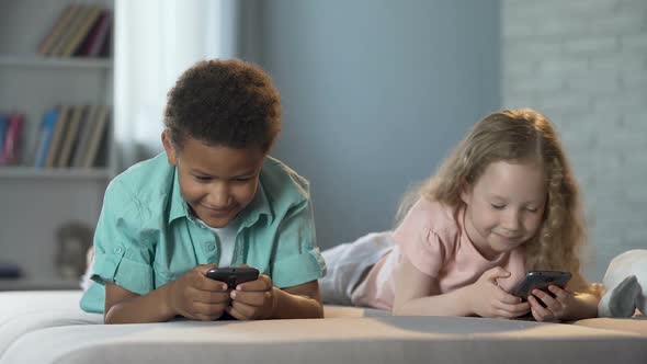 Smiling Kids Playing Online Games in Mobile Application, Addiction to Gadgets