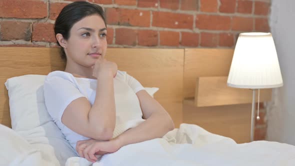 Young Indian Woman Thinking while Sitting in Bed