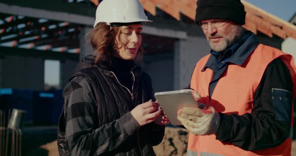 Concentrated Engineers Discussing Examining and Developing at Construction Site