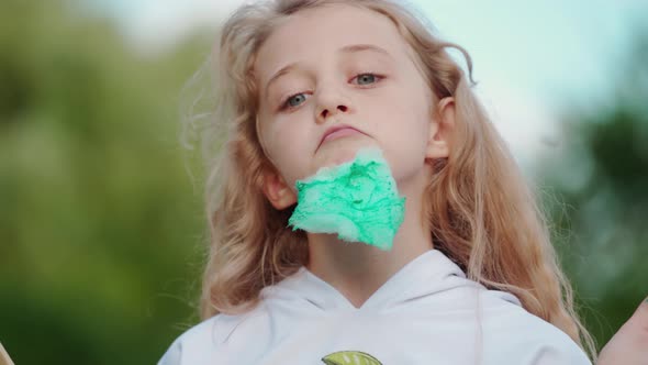 Funny girl with green cotton candy outdoors