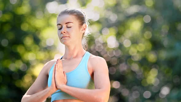 Concentrated lady yoga practitioner in blue top meditates standing in position