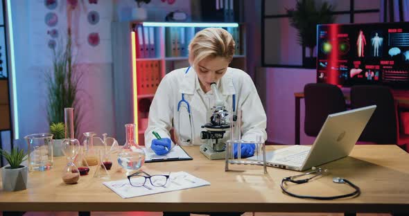 Woman Scientist Biologist in Lab Coat and Gloves Watching on Samples Under Microscope and Noting