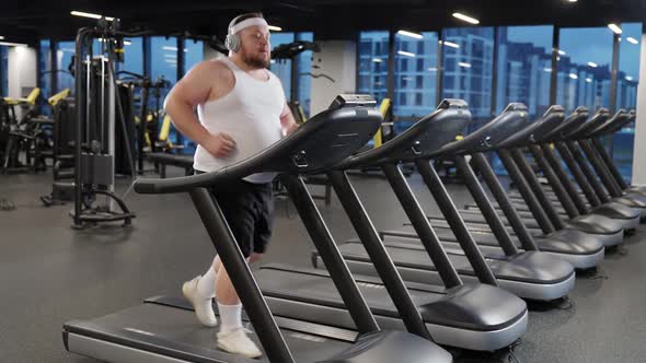 Sport Motivation Overweight Man Run on a Treadmill and Listening to Music with Headphones Aerobic