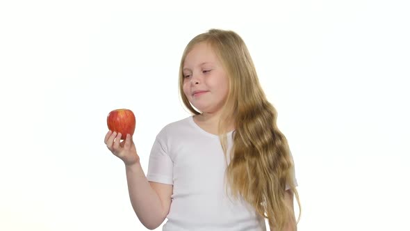 Children Girl Bites an Apple and Shows a Thumbs Up. White Background