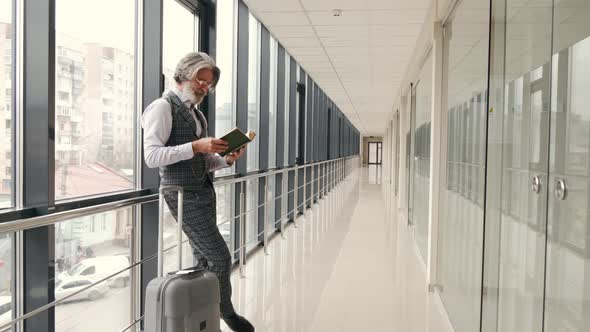 Mature Businessman in Suit Reading in the Airport Terminal