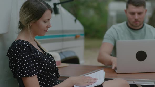 Traveler Man working at laptop and woman reading the book in summer camping