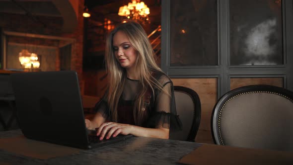 Happy Young Woman Drinking Coffee and Using Tablet Computer in Cafe