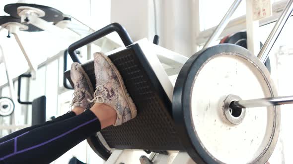 Female Legs Training on Machine Press in Gym.