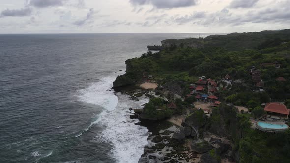 Aerial view of tropical beach in Gunung kidul, Indonesia with green and rocky cliff.