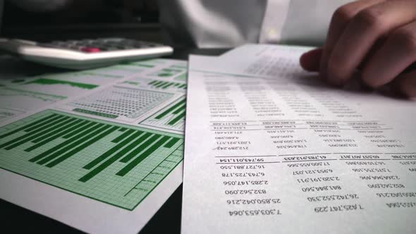 Accountant analyzing business marketing data on paper dashboard at office table.