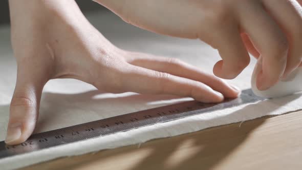 Close Up of Artisan Hands Measuring Marking and Cutting Fabric Material