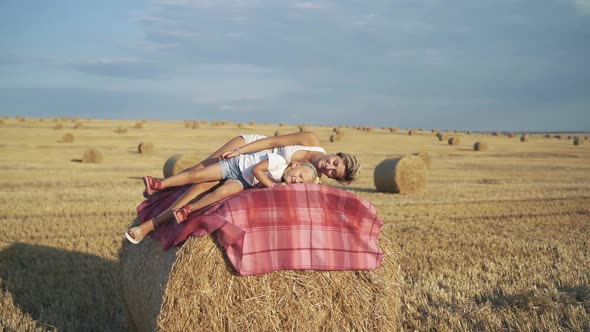 Happy Family Having Relax on a Haycock on a Sunny Day in Field