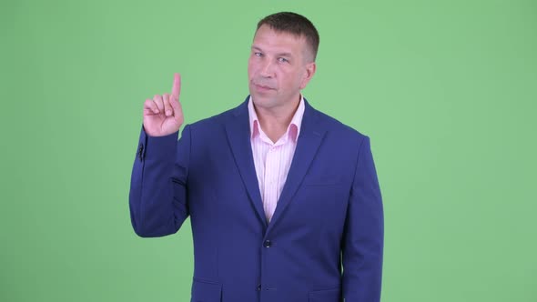 Mature Macho Businessman in Suit Pointing Up