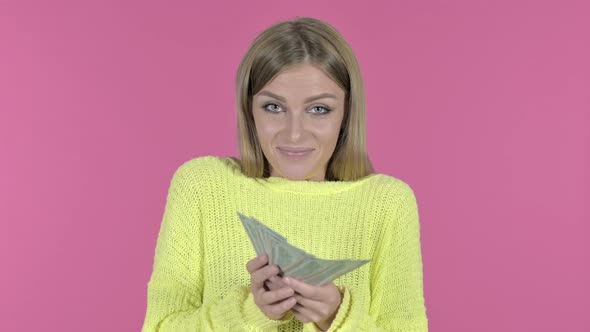 Happy Young Girl Holding Money and Smiling, Pink Background