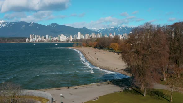 Aerial rise over picturesque Kitsilano Beach and the beautiful Vancouver skyline.