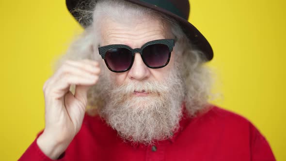 Bearded Senior Man Putting on Sunglasses and Adjusting Mustache