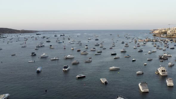 Aerial shot flying over hundreds of anchored yachts in a sea bay,Malta.