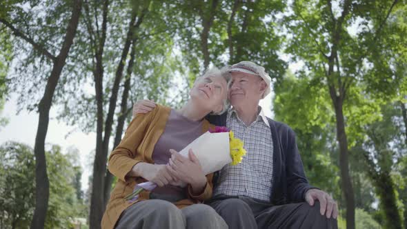 Portrait of a Mature Couple in Love Sitting on a Bench in the Park