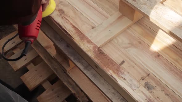 a Man Polishes the Boards with a Sandpaper and a Grinder Tool