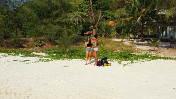 Beautiful ladies happy together on paradise resort beach wildlife by blue green ocean and white sand