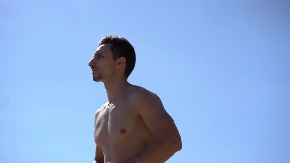 Muscular Shirtless Man Running Against Blue Sky