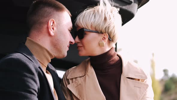 Couple Sitting on Car Trunk Looking at Each Other