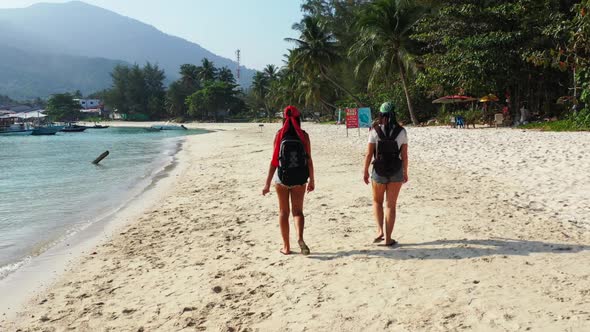 Female models best friends on beautiful tourist beach journey by shallow lagoon and white sand backg