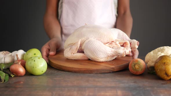  raw whole chicken and vegetables on tiles background 