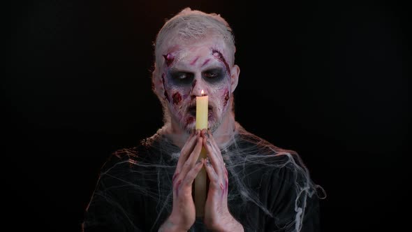 Frightening Man with Halloween Zombie Bloody Makeup Spells Conjures Over Candle Voodoo Rituals