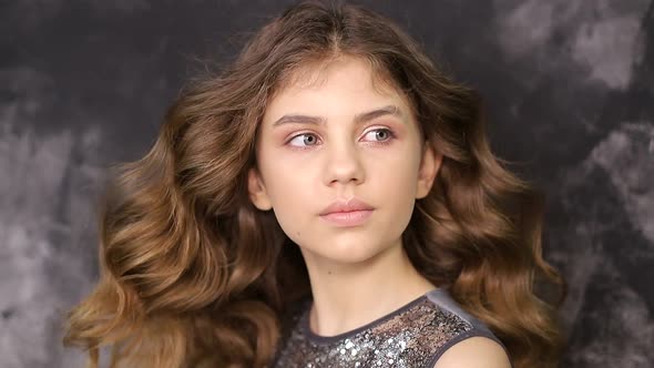 Portrait of a schoolgirl girl on a gray background. A beautiful child