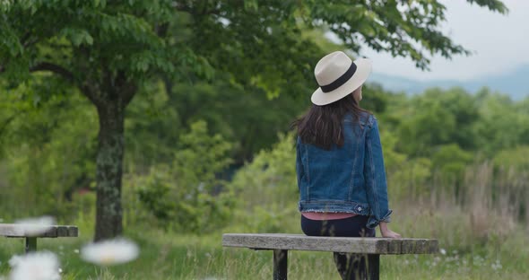 Woman look around the landscape and sit on the wooden bench